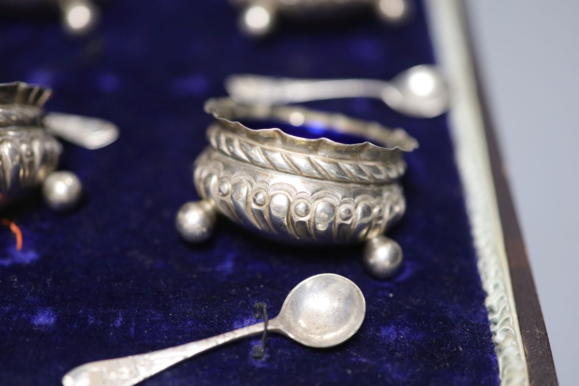 A cased set of four Victorian repousse silver salts, Matthew John Jessop, Birmingham, 1887, 5cm, and four associated spoons.